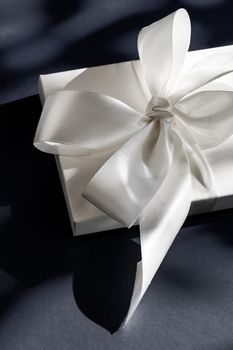 Anniversary celebration, shop sale promotion and luxe surprise concept - Luxury holiday white gift box with silk ribbon and bow on black background, luxe wedding or birthday present