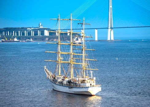 Vladivostok, Russia. Seascape with a beautiful sailboat on the background of the Russian bridge.