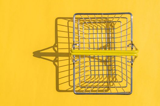 steel supermarket basket with hard shadow on colored background. High quality photo