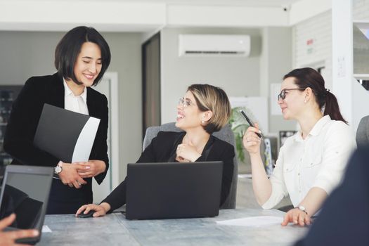 Three young successful business women in the office, together, happily working on a project. 