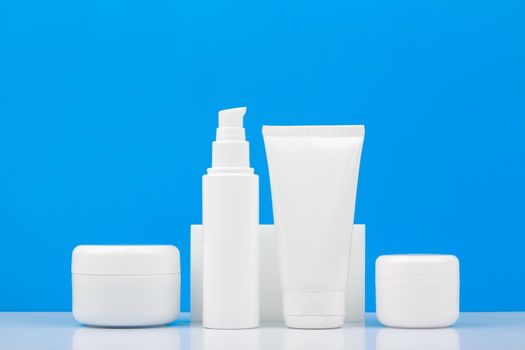 Set of cosmetic bottles on white table against blue background. Concept of male's skin and body care and hygiene