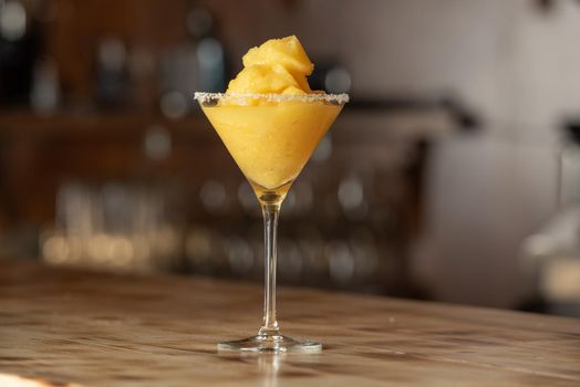 Frozen margarita cocktail on wooden bar.