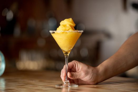 Frozen margarita cocktail on wooden bar.