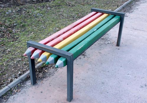 Bench in the park in the form of large multi-colored pencils.