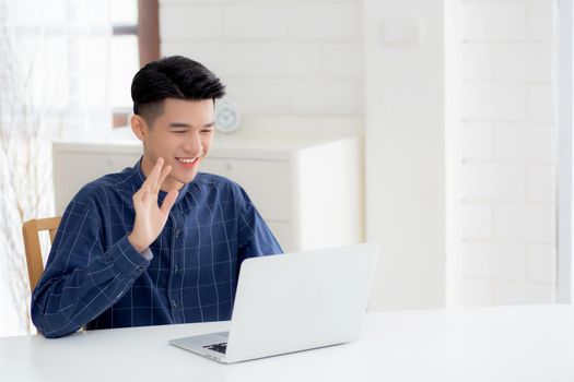 Young asian business man using laptop computer for video call online hello and communicate work from home, male conference with notebook and say hi, social distancing, communication concept.