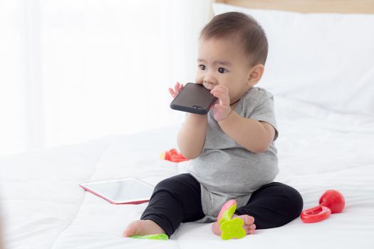 Portrait of cute little baby girl sitting with cozy on bed at bedroom, happiness of toddler, newborn 6-11 months with innocence and expression with cheerful, child charm, indoors, one person.