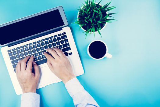 Flat lay, hand of businessman working on Laptop computer with plant and cup of coffee on desk in office, workplace and notebook and potted tree, workspace and copy space, top view, business concept.