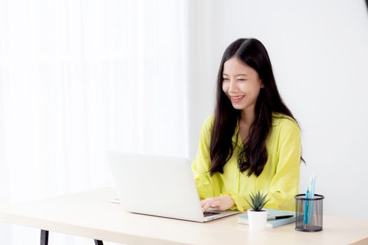Young asian businesswoman working on laptop computer on desk at home office, freelance looking and typing on notebook on table, lifestyle of woman studying online, business and education concept.