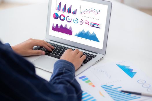 Young asian business man working laptop computer blank display screen while report graph and chart paper on desk, businessman analysis statistic of finance on table, planning for success, indoor.