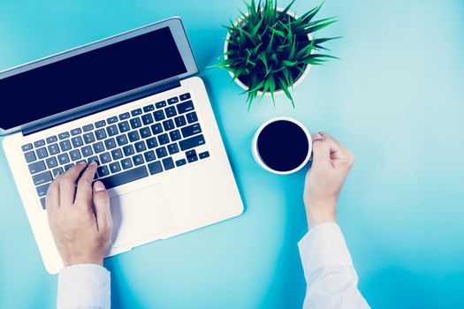 Flat lay, hand of businessman working on Laptop computer with plant and cup of coffee on desk in office, workplace and notebook and potted tree, workspace and copy space, top view, business concept.