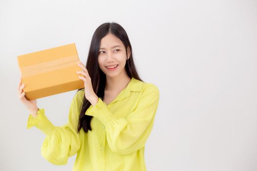 Young asian woman smiling and holding cardboard box with surprise at home, happy female carrying parcel box with excited, present and gift, packaging for deliver, online shopping store and service concept.