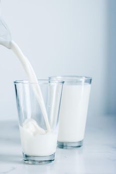 Dairy, healthy nutrition and breakfast concept - World Milk Day, pouring into glass on marble table