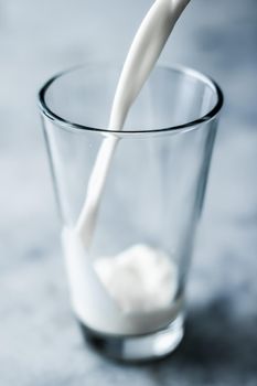 Dairy, healthy nutrition and breakfast concept - World Milk Day, pouring into glass on marble table