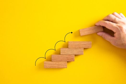 Ladder career path for business growth success process concept. Hand arranging wood block stacking as stair stair with arrow up.