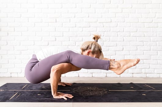 Active lifestyle. Young attractive woman wearing sportswear practicing yoga at home. Indoor full length, white brick wall background