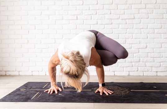 Active lifestyle. Young attractive woman wearing sportswear practicing yoga at home. Indoor full length, white brick wall background