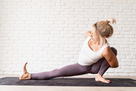 Active lifestyle. Young attractive woman wearing sportswear practicing yoga at home. Indoor full length, white brick wall background