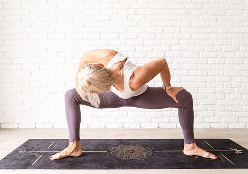 Active lifestyle. Young attractive woman wearing sportswear practicing yoga at home. Indoor full length, white brick wall background