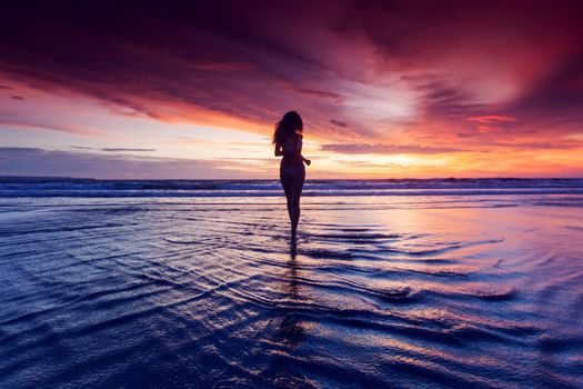 Woman running on the beach at sunset in bikini. Bali island, Indonesia