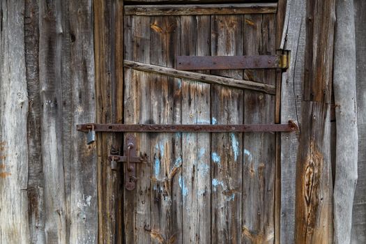 old wooden barn door with iron padlocks and rustes steel reinforcement bands.