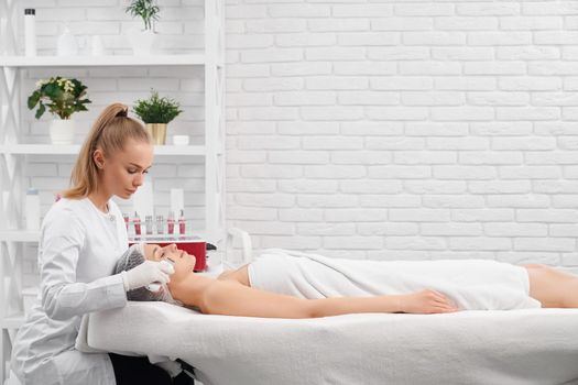 Side view of young beautiful woman lying on procedure for cleaning face with special modern professional equipments. Concept of process care for skin face and body in beauty salon. 