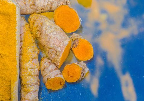 Turmeric powder (Kurkuma) in a wooden spoon and roots 