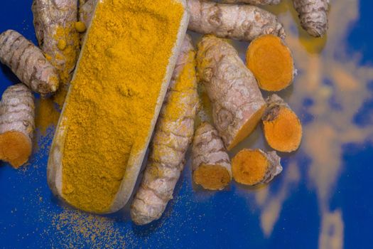 Turmeric powder (Kurkuma) in a wooden spoon and roots 