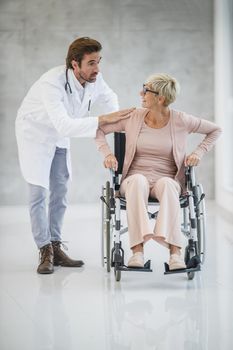 Shot of a young doctor helping a senior female patient in a wheelchair.