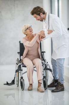Shot of a young doctor helping a senior female patient in a wheelchair.