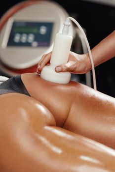 Shot of an unrecognizable woman getting anti cellulite massage at the beauty salon. She have an ultrasound cavitacion treatment to fat reduction.