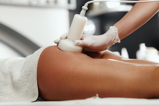 Shot of an unrecognizable woman getting anti cellulite massage at the beauty salon. She have an ultrasound cavitacion treatment to fat reduction.