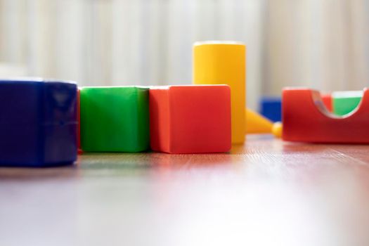 Multi-colored large cubes are randomly scattered on the floor in the children's playroom, close-up.