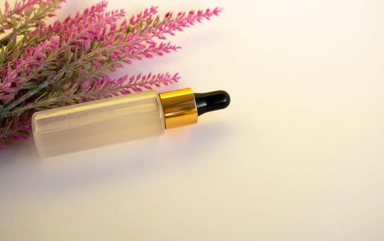A bottle of cosmetic liquid transparent gel next to a branch of artificial lavender on a white background. Flat styling style