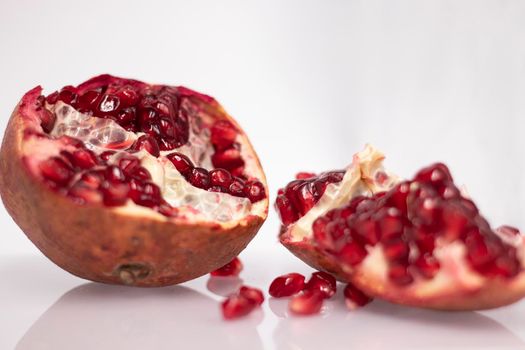 ripe fresh sliced pomegranate fruit with red seeds isolated on white background