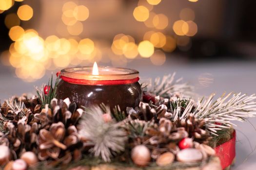 Christmas decor made of tree branch with new years toys on it and a candle in it.