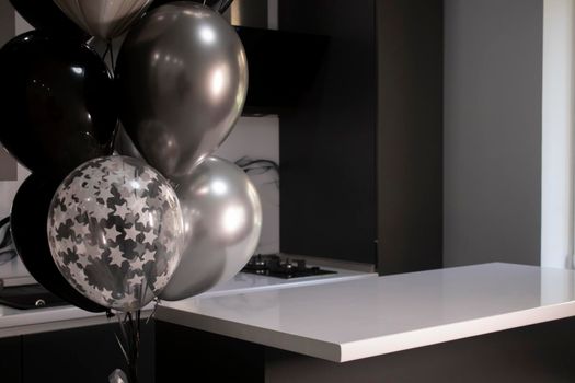 Corner of stylish Minimalistic grey kitchen, dark gray cupboards, white countertops and bar. black and white balloons. High quality photo