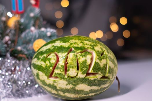 watermelon with 2021 carved number next to new year decorations. christmas theme.