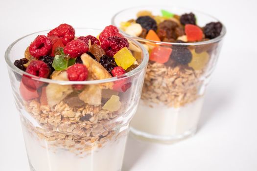 muesli dessert with yogurt and candied or dried fruits with raspberries on top in glass isolated on white background. breakfast Granola