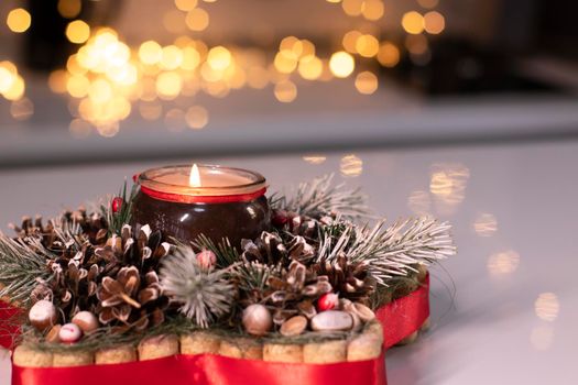 Christmas decor star-shaped made of tree branch with new years toys on it and a candle in it.