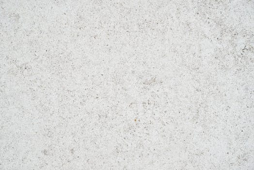 The subtle white textured surface of an external concrete wall. The wall is lightly speckled.