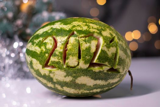 watermelon with 2021 carved number next to new year decorations. christmas theme.