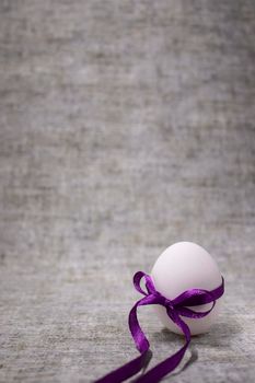 chicken egg wrapped in purple bow-knot. healthy raw food. easter egg, present.