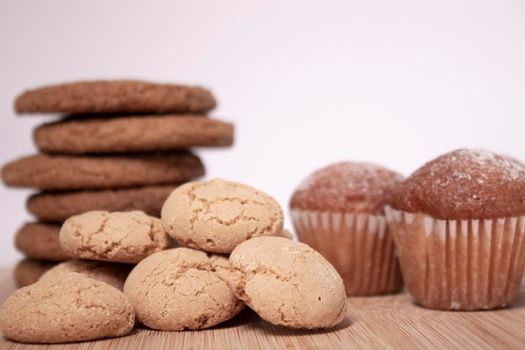 muffins, almond amaretti and oat cookies on wooden stand board. concept of sweet bakery