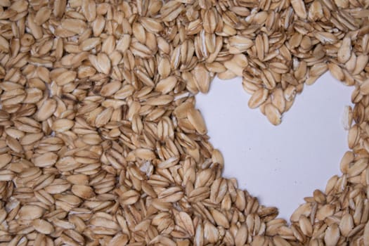 oatmeal texture with a heart painted in the middle on a white background. oat flakes. Healthy breakfast concept. Muesli cereals