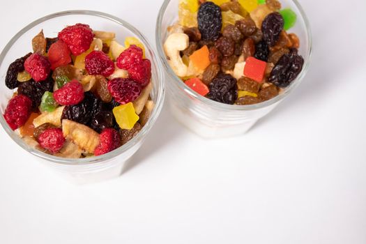 muesli dessert with yogurt and candied or dried fruits with raspberries on top in glass isolated on white background. breakfast Granola