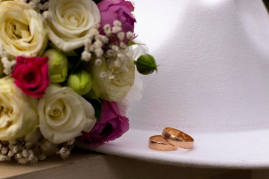 wedding rings on a white stylish hat next to the bride's bouquet. marriage concept.