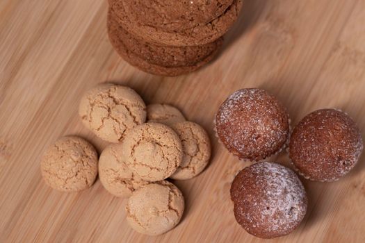 muffins, almond amaretti and oat cookies on wooden stand board. concept of sweet bakery