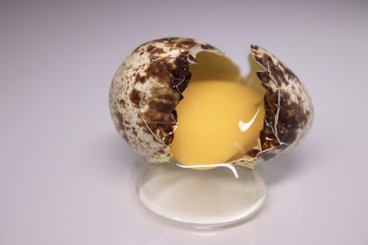 broken Quail egg isolated on white background with leaking white and yolk. healthy raw food.