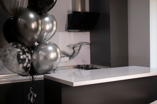 Corner of stylish Minimalistic grey kitchen, dark gray cupboards, white countertops and bar. black and white balloons. High quality photo