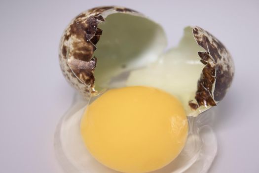 broken Quail egg isolated on white background with leaking white and yolk. healthy raw food.